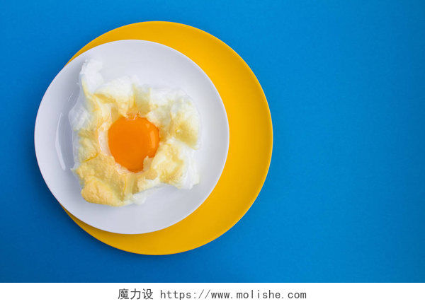 蓝色背景上一碟煎鸡蛋鸡蛋在云中的五颜六色的盘子在蓝色的背景。顶部视图。复制空间.